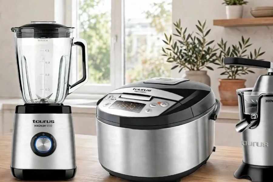 Espressor, blender, multicooker și storcător Taurus aliniate pe blatul unei bucătării, lângă fereastră